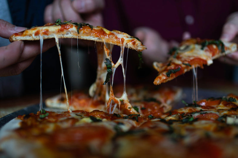 A hand pulling a slice from a whole pizza