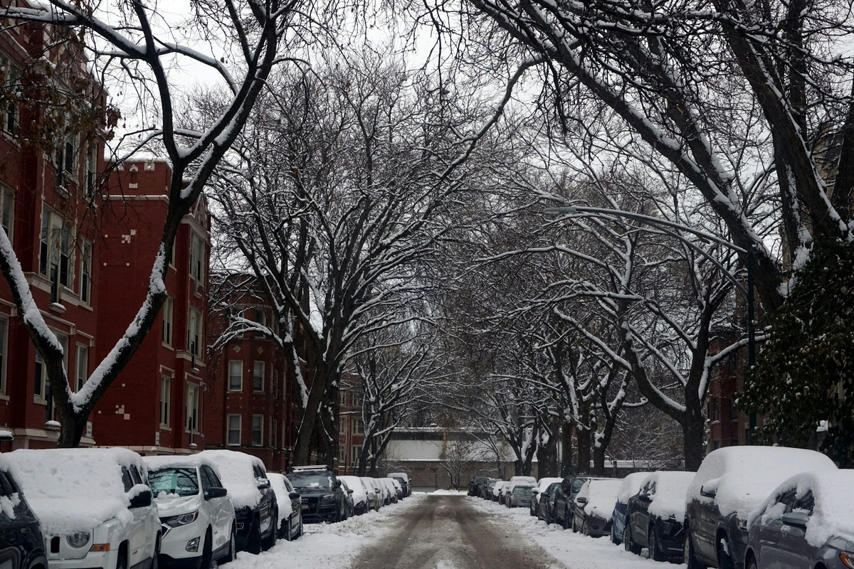 A snow-covered street lined with parked cars