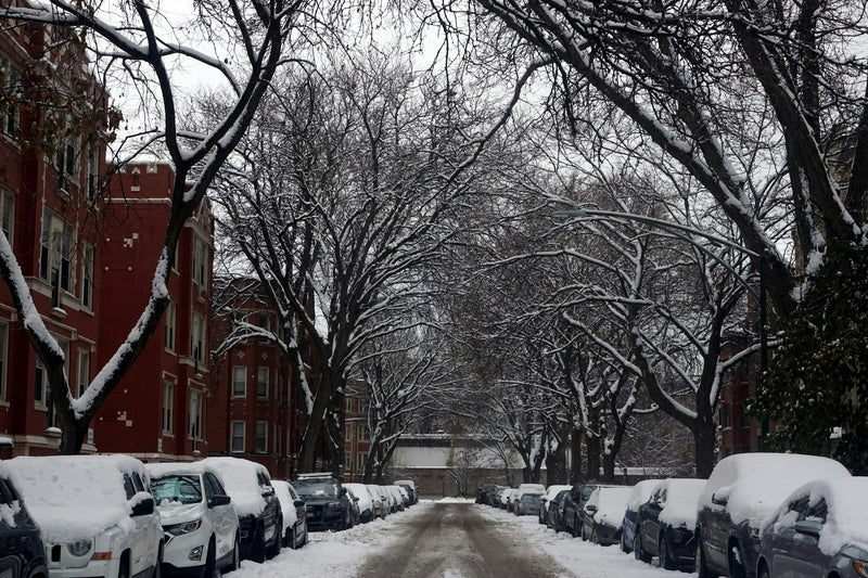 A snow-covered street lined with parked cars
